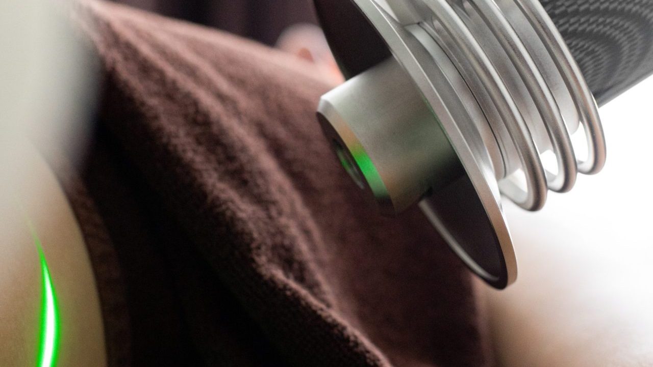 A green laser of a Nextern medical device traces an area on a patient’s body. 